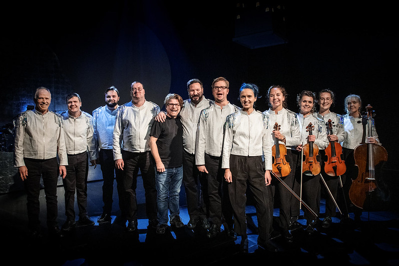 Rivissä orkesterin kymmenen soittajaa, säveltäjä Markus Fagerudd ja kapellimestari Emma Raunio. Kolmella orkesterin soittajalla on viulut kädessään ja yhdellä sello. 