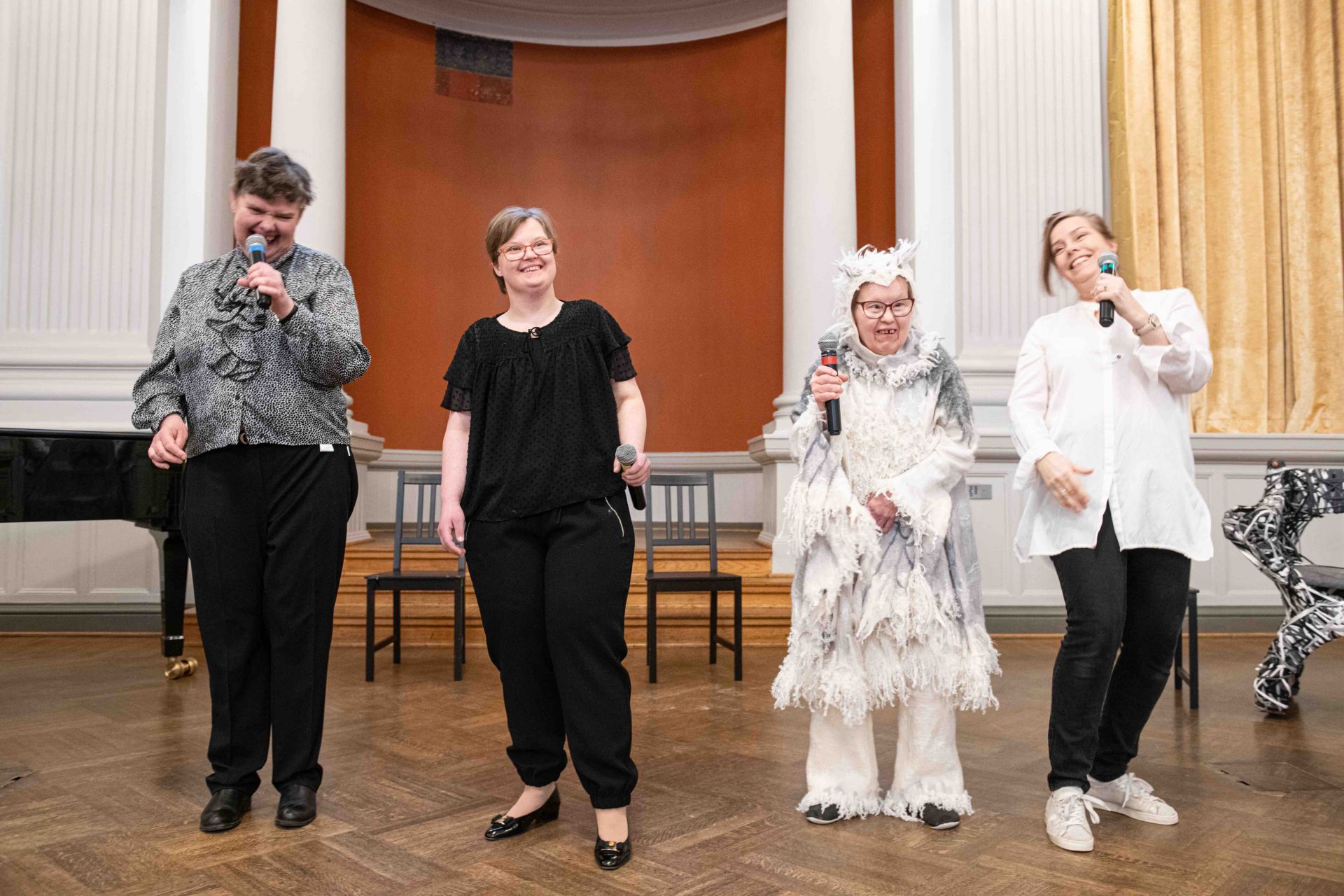 Från vänster till höger: DuvTeaterns skådespelare Yvonne Heinz, Karolina Karanen, Irina von Martens och sångaren Martina Roos. Kvinnorna håller i varsin mikrofon och är uppklädda till fest. von Martens har på sig en uggledräkt från sin roll i pjäsen “I det stora landskapet”.