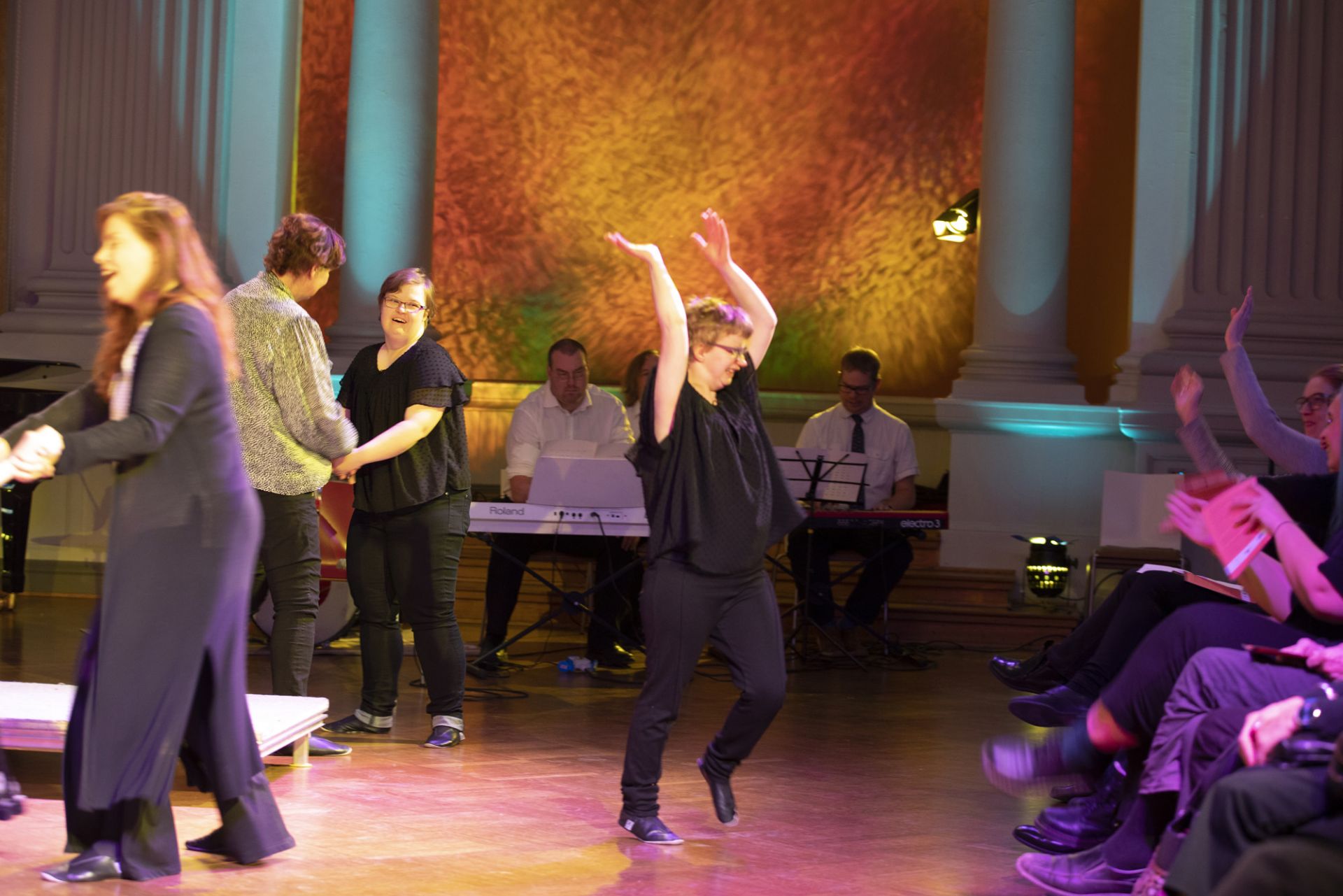 Tanya Palmgren visar hur publiken skall komma med i sången Drömmen om Elin. Resonaarigroup spelar och några skådespelare dansar.